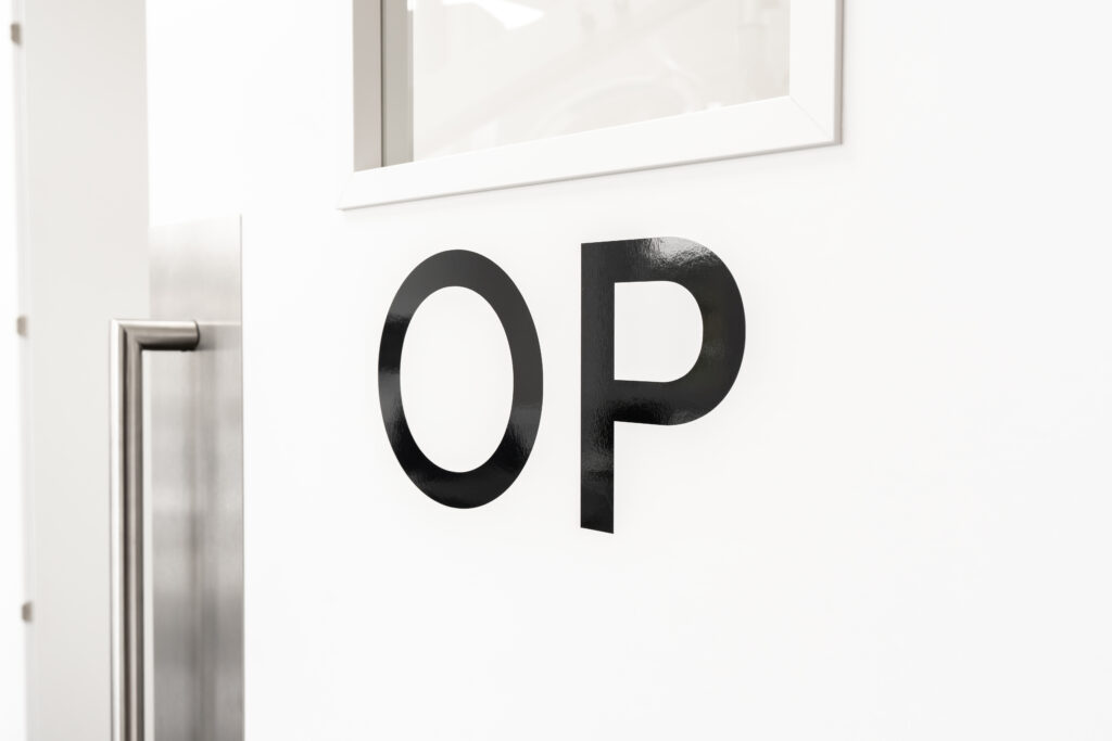 Weiße Tür mit der Aufschrift ‚OP‘ in der Zahnklinik Nordhorn – moderner und hygienischer Eingangsbereich zum Operationsraum.