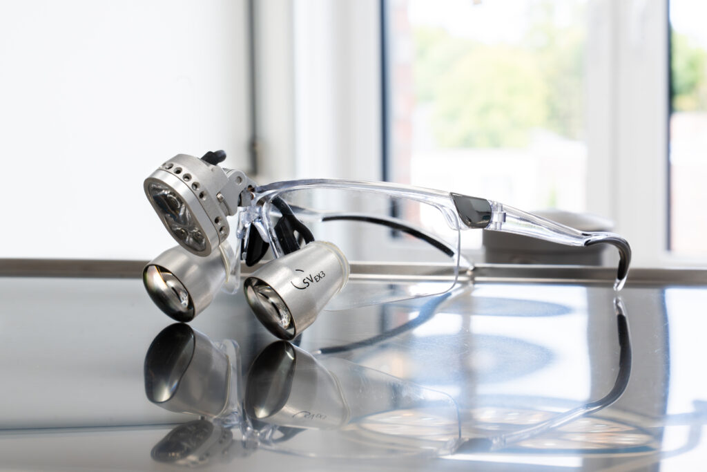 Zahnarzt-Lupe mit integrierter LED-Beleuchtung liegt auf einem Metalltisch – Präzisionsinstrument für detailgenaue zahnärztliche Eingriffe.